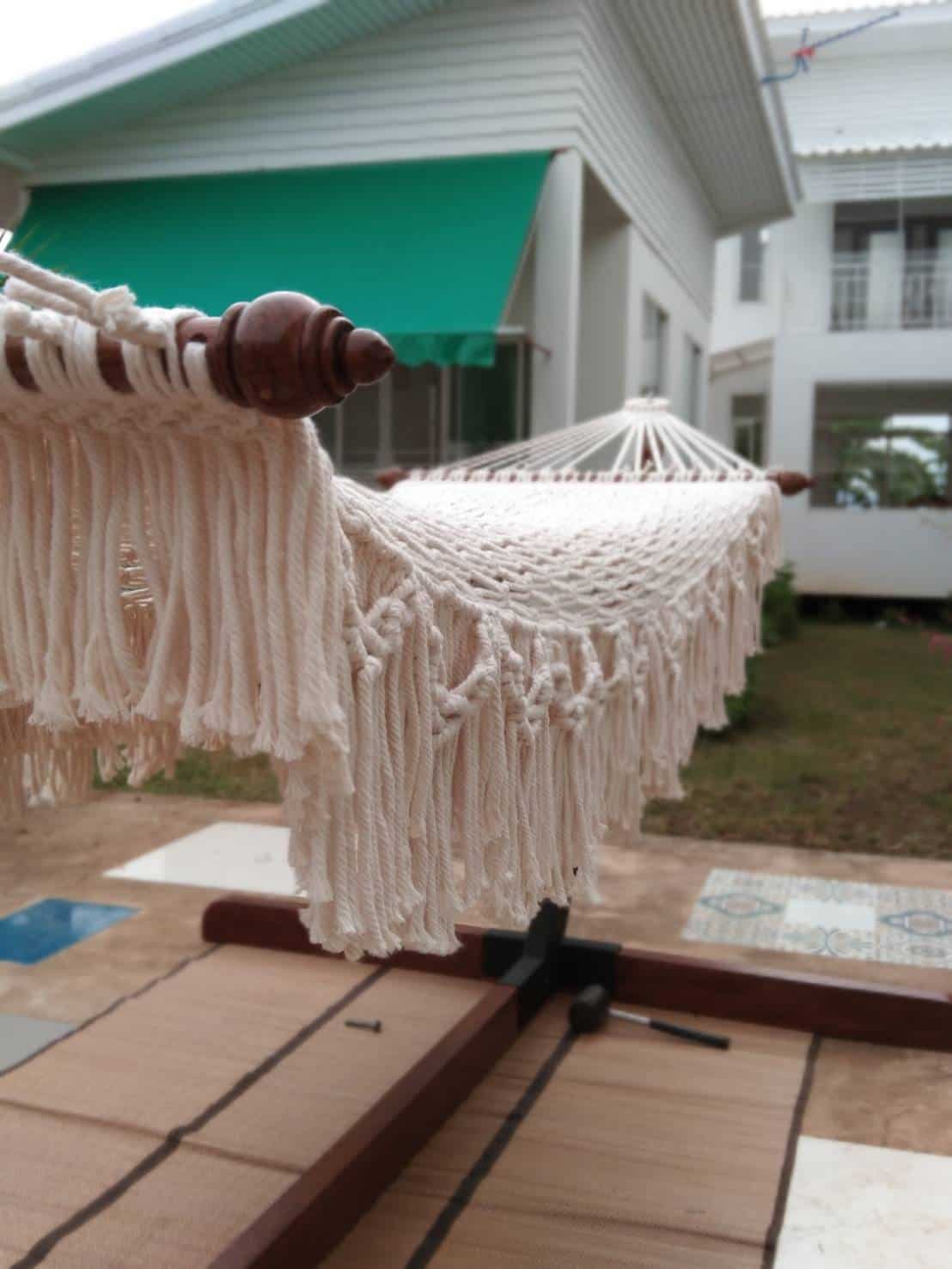 close-up outdoor beige fringe rope hammock and wooden stand for patio relaxation.