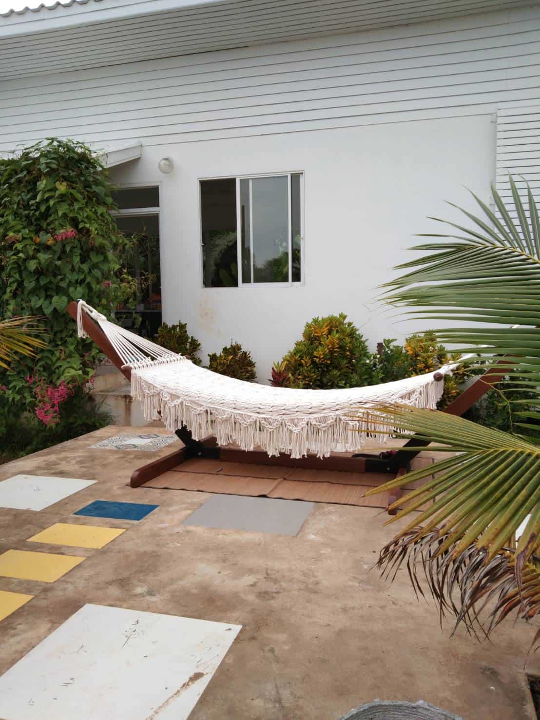 Outdoor beige fringe rope hammock and wooden stand for patio relaxation.