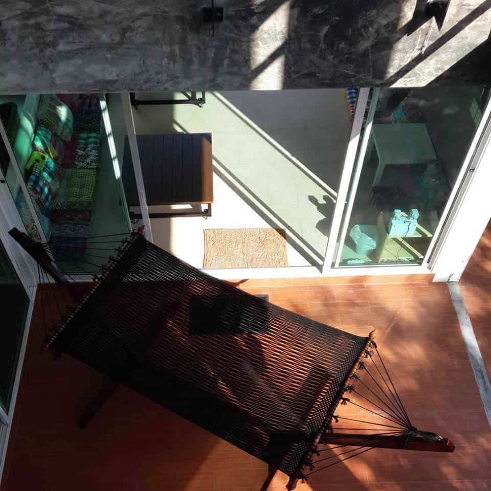 black cotton rope hammock and stand on a terracotta-tiled patio.