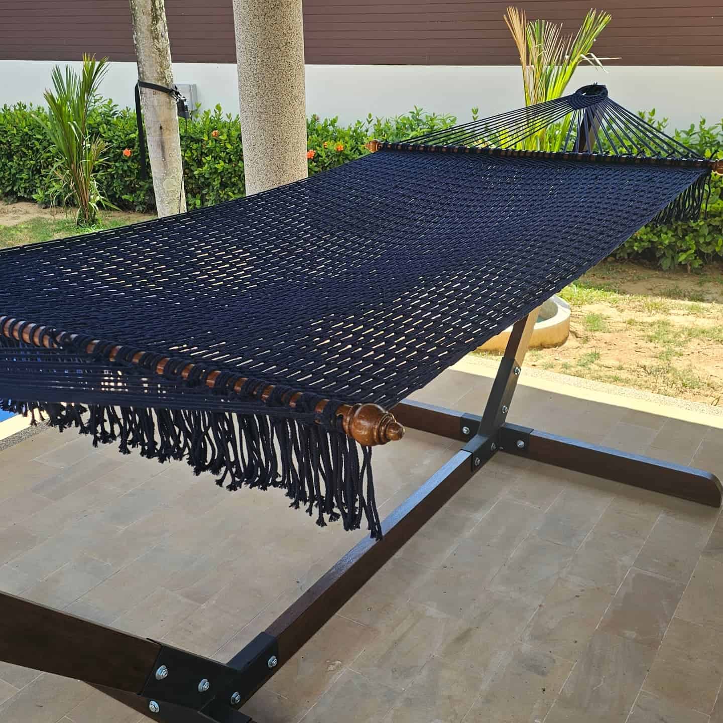 Midnight blue cotton rope hammock and wooden stand for patio or backyard relaxation.