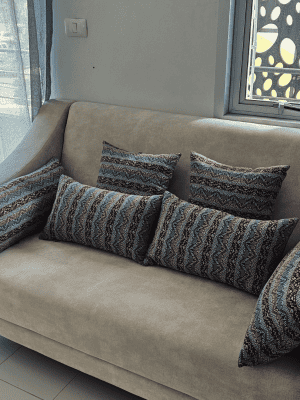 Neutral color sofa with five throw pillows in blue and red tribal stripe geometric pattern