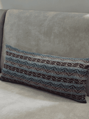 Rectangular lumbar pillow featuring a horizontal red and blue tribal geometric pattern