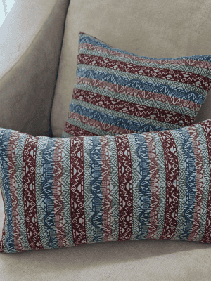 two blue and red tribal patterned throw pillows resting on a neutral beige sofa