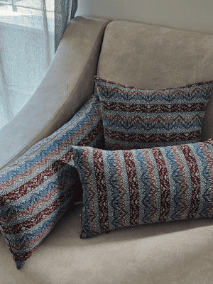 three blue and red tribal patterned throw pillows resting on a neutral beige sofa