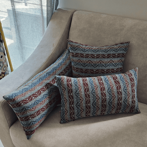three blue and red tribal patterned throw pillows resting on a neutral beige sofa