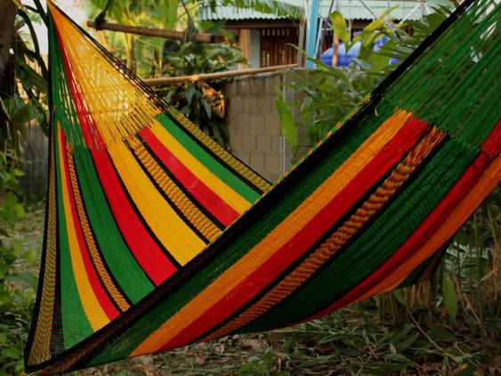 Woven net hammock chair, "Rasta New" pattern, with distinct vertical sections of red, green, and bright yellow/gold stripes, inspired by the Rasta colors.