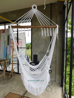 Bohemian white cotton hammock chair for indoor use, shown in a modern space with concrete finishes and a bright natural environment view.