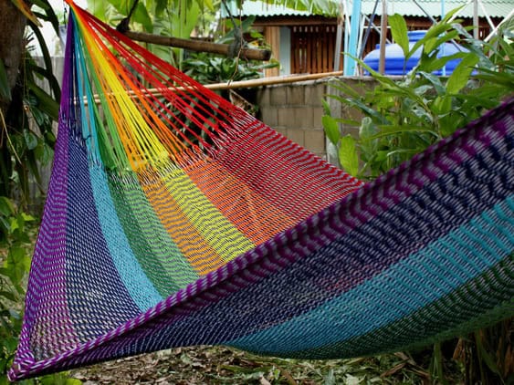 Woven net hammock chair, "Pale Rainbow" pattern, featuring soft, muted rainbow colors (lavender, pastel blue, pale green, pink) in a gentle, striped gradient.