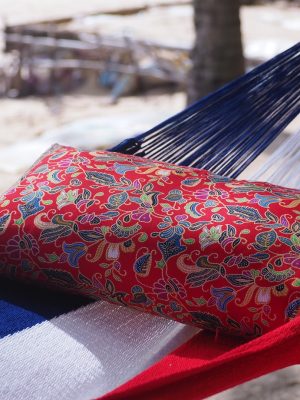 Detail of the blue, white, and red striped fabric of the Dutch hammock, demonstrating the tight weave and the contrast with the patterned red pillow.