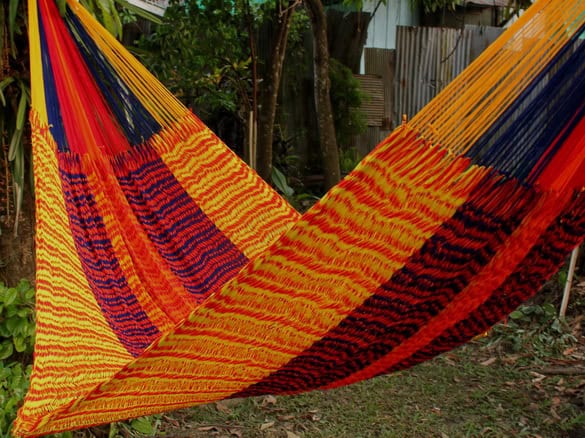 ULA "Sokrates" hanging hammock chair in a bold blend of navy blue, bright yellow, and orange stripes, featuring a richly patterned weave for a modern, cozy look.