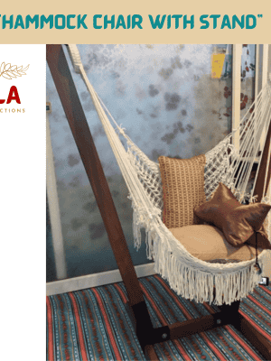 Macrame hammock chair with stand from ULA Collections, featuring white woven cotton and a decorative fringe. The chair sits on a dark wood A-frame stand indoors, accessorized with brown cushions and a patterned rug.