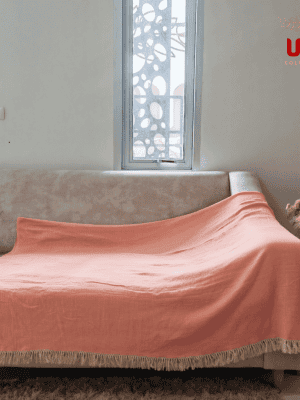 Peach Sulu crinkle gauze throw blanket with fringe fully covering a sofa