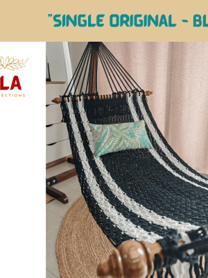 Handmade black and white striped cotton rope hammock with wooden spreader bars and a tropical print pillow