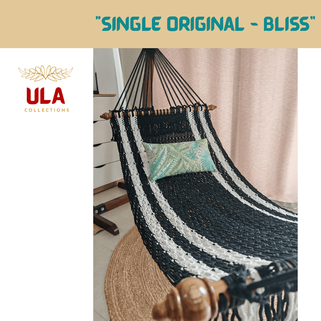 Handmade black and white striped cotton rope hammock with wooden spreader bars and a tropical print pillow