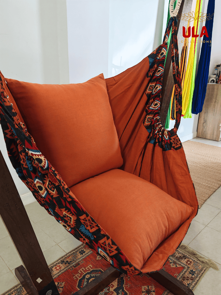 Aztec-patterned woven fabric hammock chair in burnt orange with plush cushions.