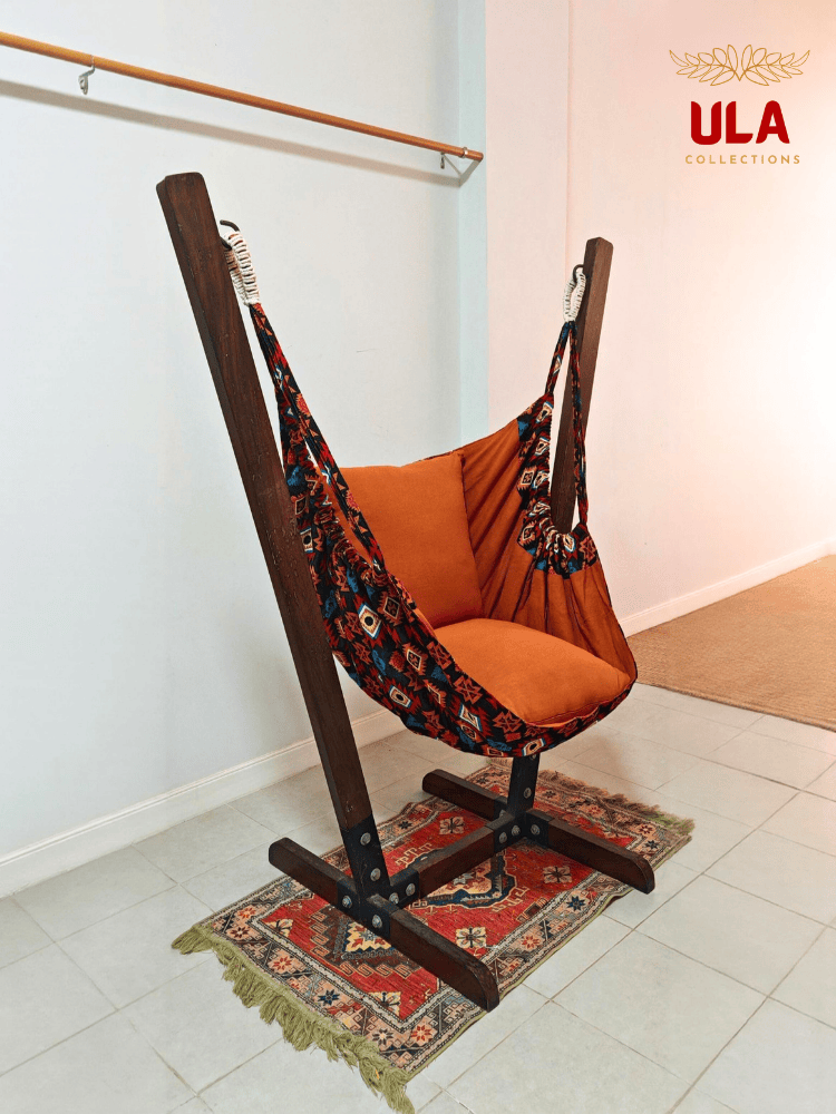 Aztec-patterned woven fabric hammock chair in burnt orange with plush cushions.