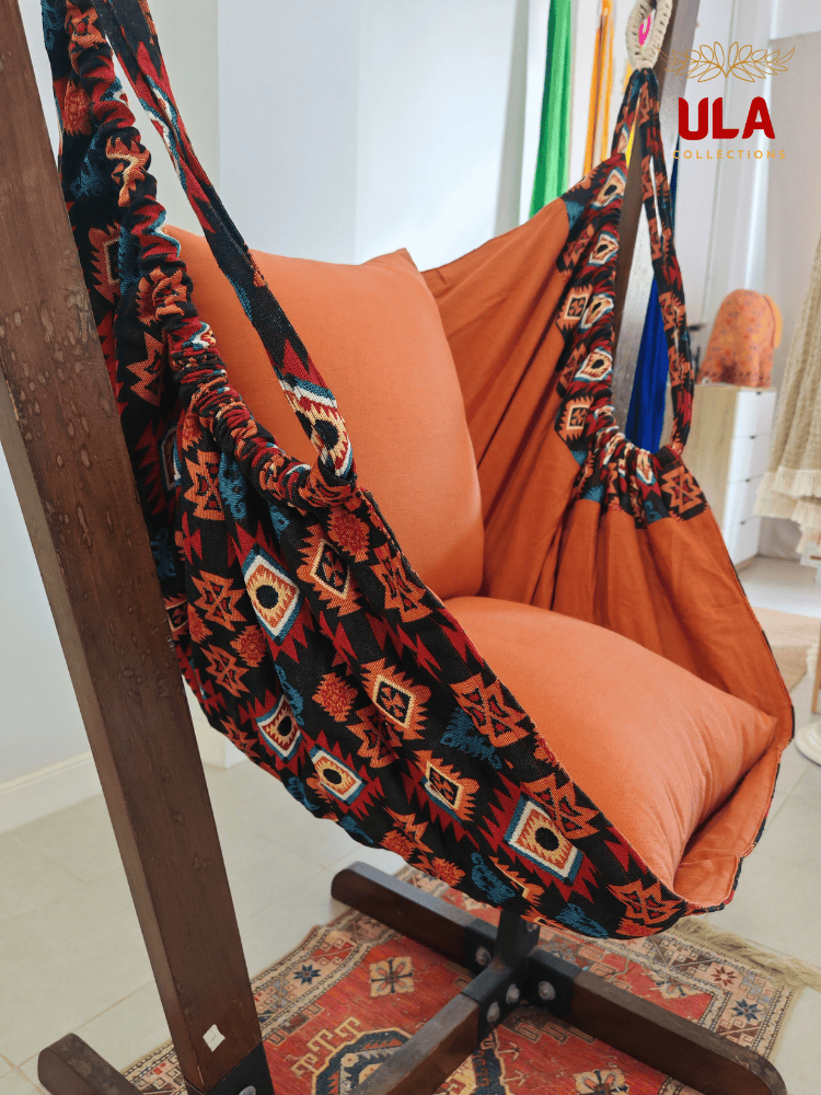 Aztec-patterned woven fabric hammock chair in burnt orange with plush cushions.