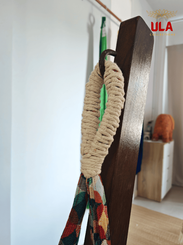 Close-up of hammock chair loop, showing the durable cream macramé reinforcement and colorful woven fabric hanging from a metal hook.