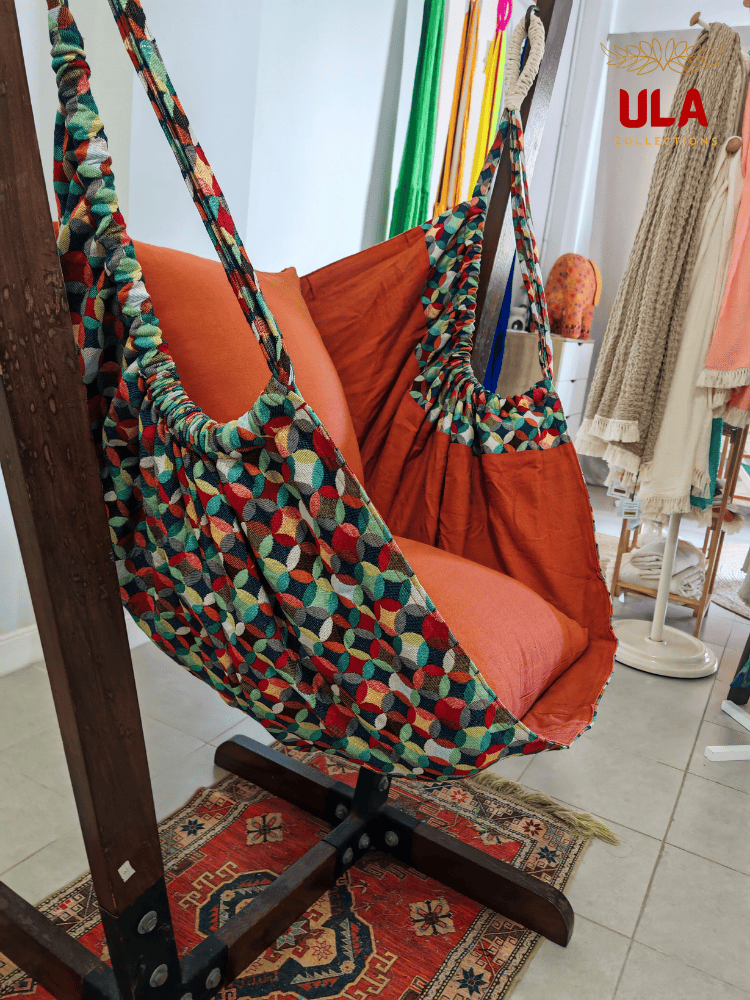 Vibrant woven fabric hammock chair featuring the Canyon multicolored overlapping circle pattern and plush orange cushions.