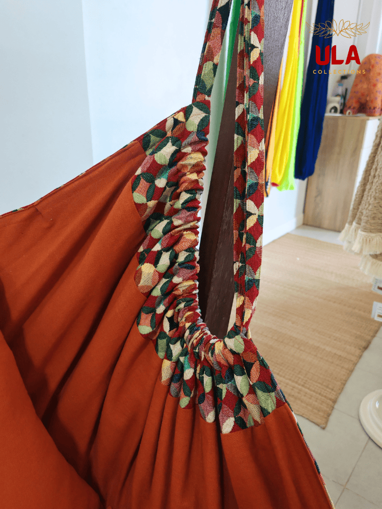 Vibrant woven fabric hammock chair featuring the Canyon multicolored overlapping circle pattern and plush orange cushions.