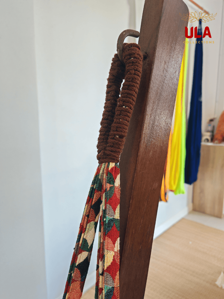 Close-up of hammock chair loop, showing the durable brown macramé reinforcement and colorful woven fabric hanging from a metal hook.
