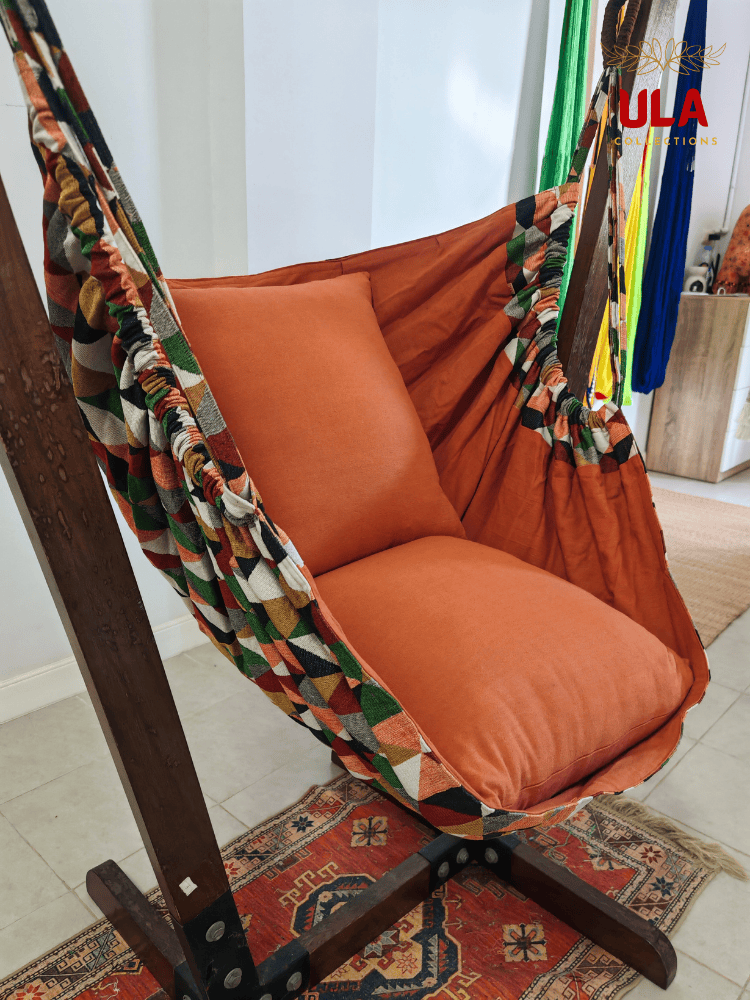 Geometric pattern woven fabric hammock chair with green, orange, and cream triangles and solid orange cushions