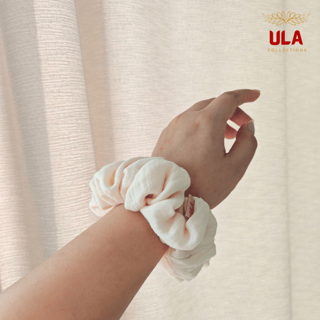 A person's wrist wearing a cream color scrunchie