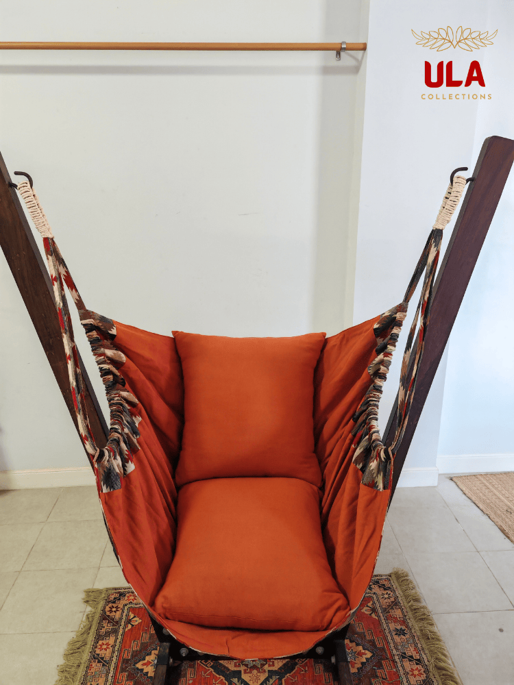 Woven fabric hammock chair with a neutral zigzag pattern in beige, brown, and red, featuring plush orange seat and back cushions.