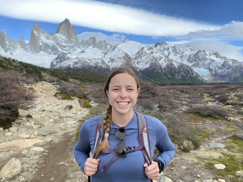 Woman smiling on a hiking trail in front of mountains