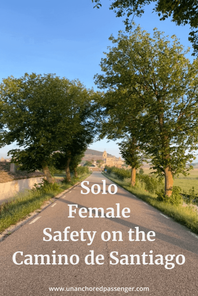 Tree-lined road into a town at sunrise with text that says "Solo Female Safety on the Camino de Santiago"