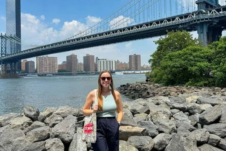 Woman smiling in front of the Manhattan Bridge in Brooklyn, New York