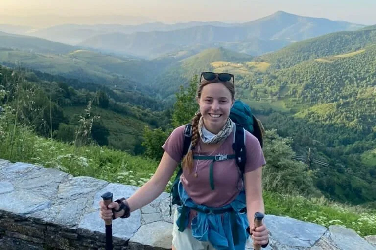 Female hiker smiling with mountains in the background