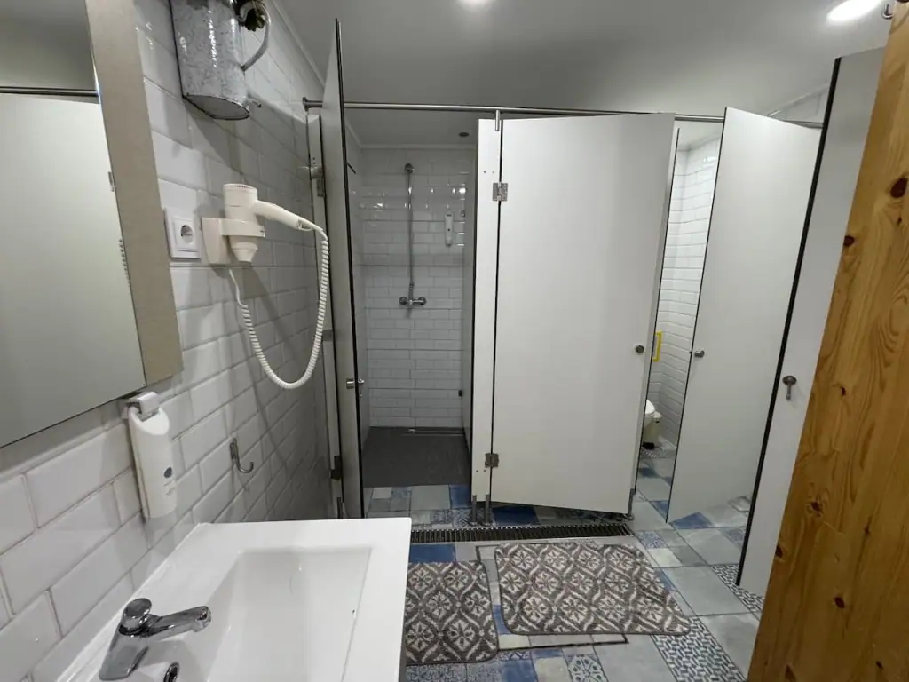 Nice bathroom at Hostel Bulwark on the Camino Portugués Central route showing two shower stalls and a sink with a hair dryer.