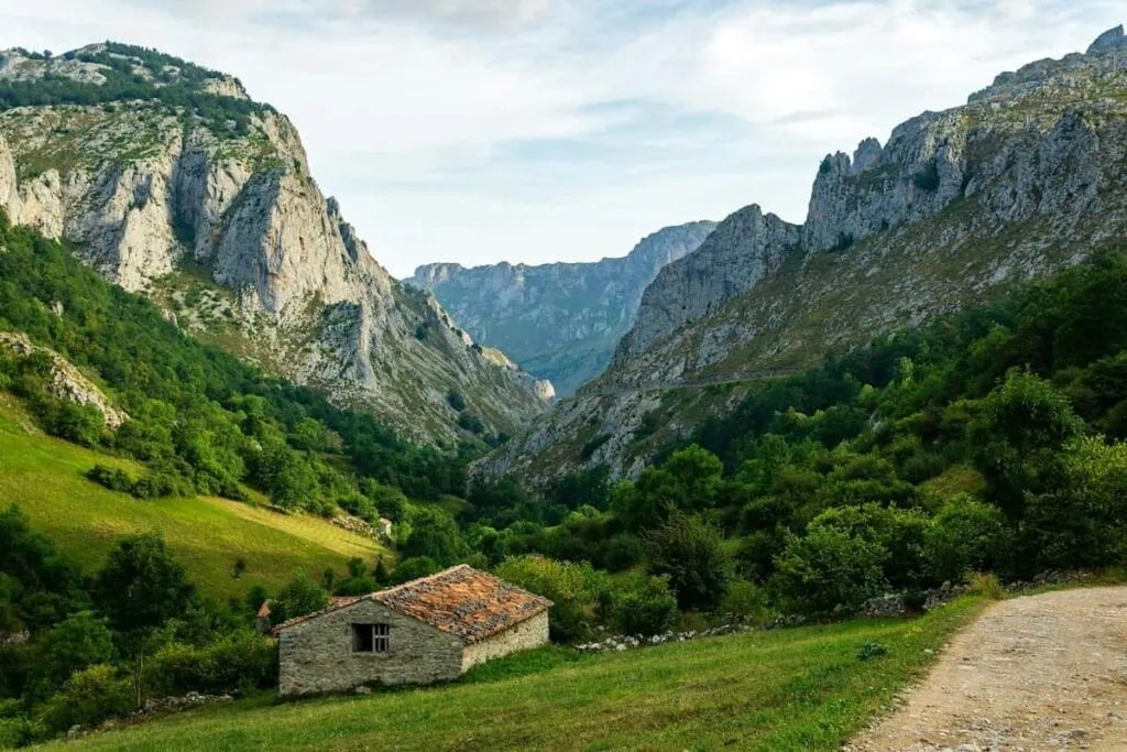 Picos de Europa mountains with a small building and a trail in the foreground.
