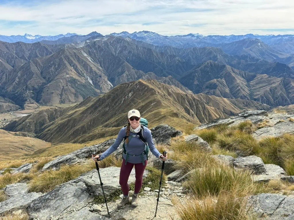 Mikala smiling with mountains in the background on Mount Lomond in New Zealand