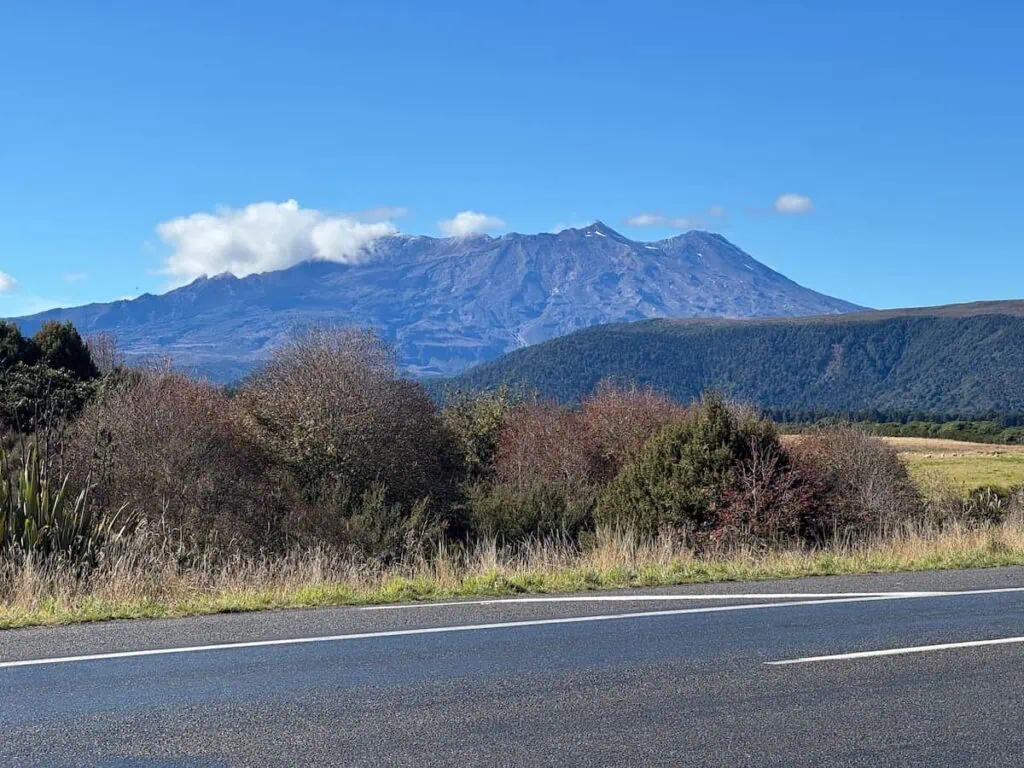 View of the volcano Mount Ruapehu looming in the distance from the main road in National Park, New Zealand.