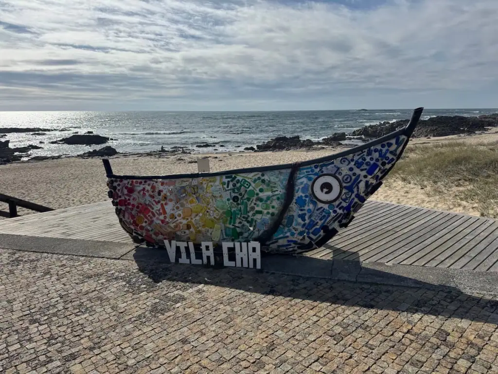 Rainbow colored painted boat that says Vila Chã on the beach with the ocean in the background along the Camino Portugués Coastal route.