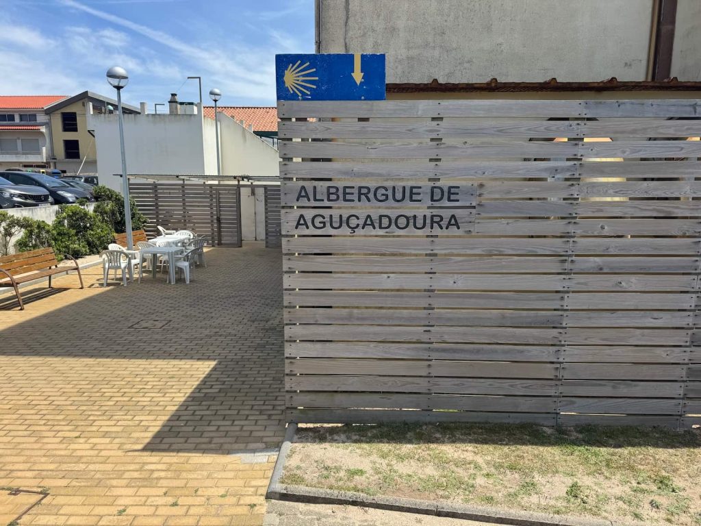 Entrance to the municipal albergue in Aguçadoura on the Camino Portugués Coastal route with a set of tables and chairs outside.