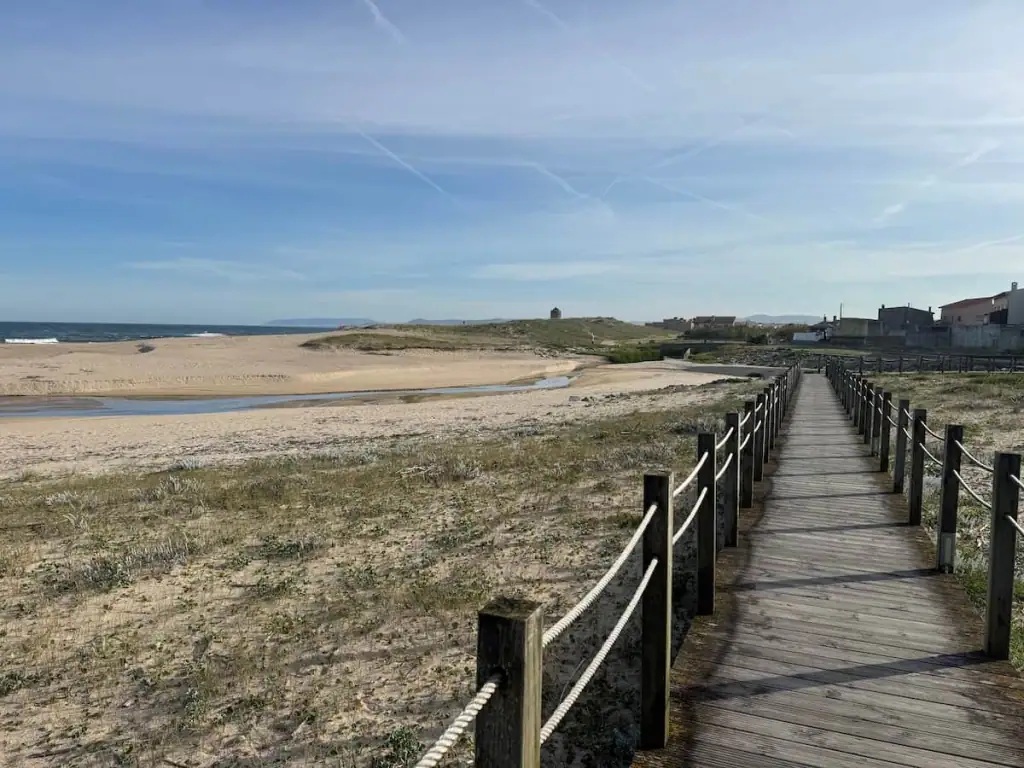 Boardwalk on the Camino Portugués Coastal route on the right side of the image stretching ahead with beaches and the ocean to the left.