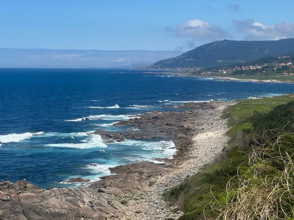 Bright blue ocean meeting the rocky coastline with some small mountains in the distance along stage 6 of the Camino Portugués Coastal route.