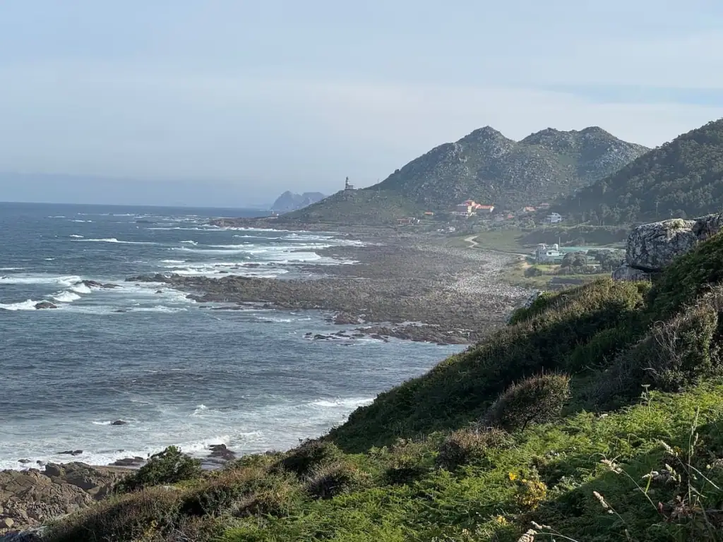 Small mountains along the coastline just south of Mougás, Spain along the Camino Portugués Coastal with rough waves coming in and a mist in the air.