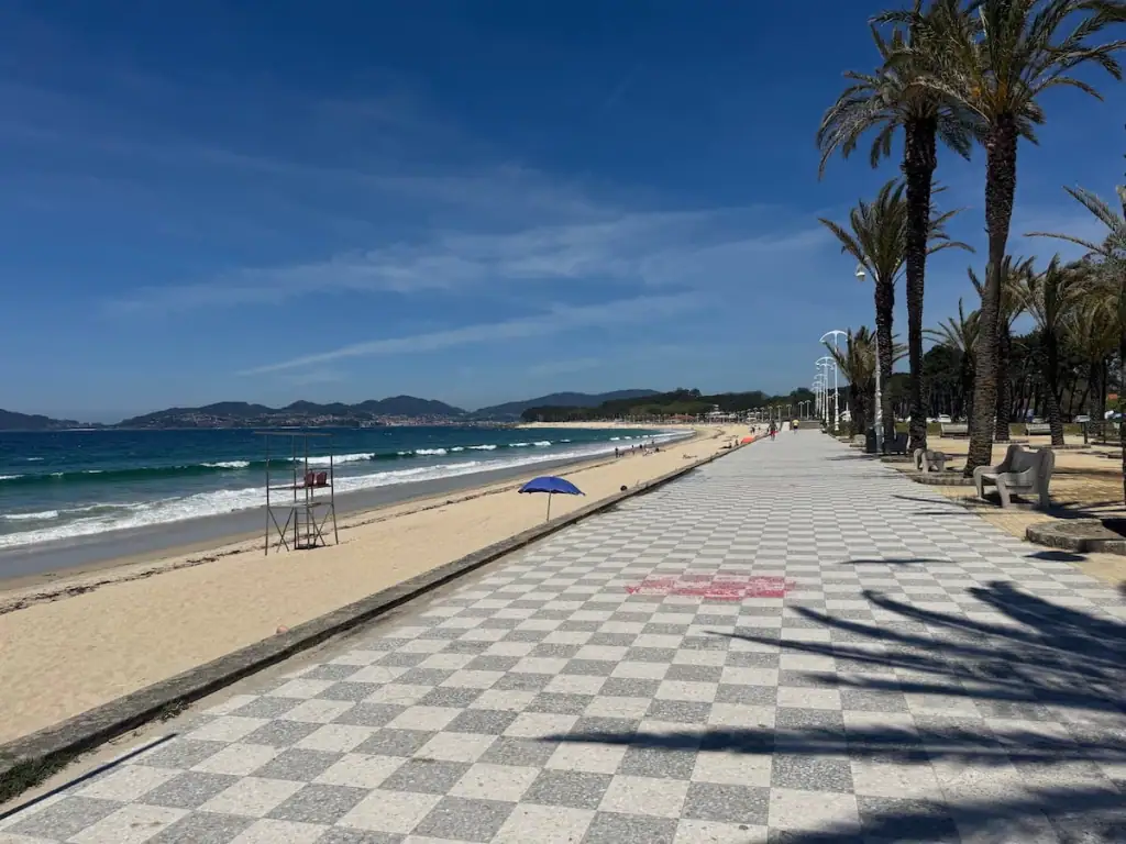 Gray and white checkered walkway along a beach with palm trees in Samil outside of Vigo along the Litoral Way.