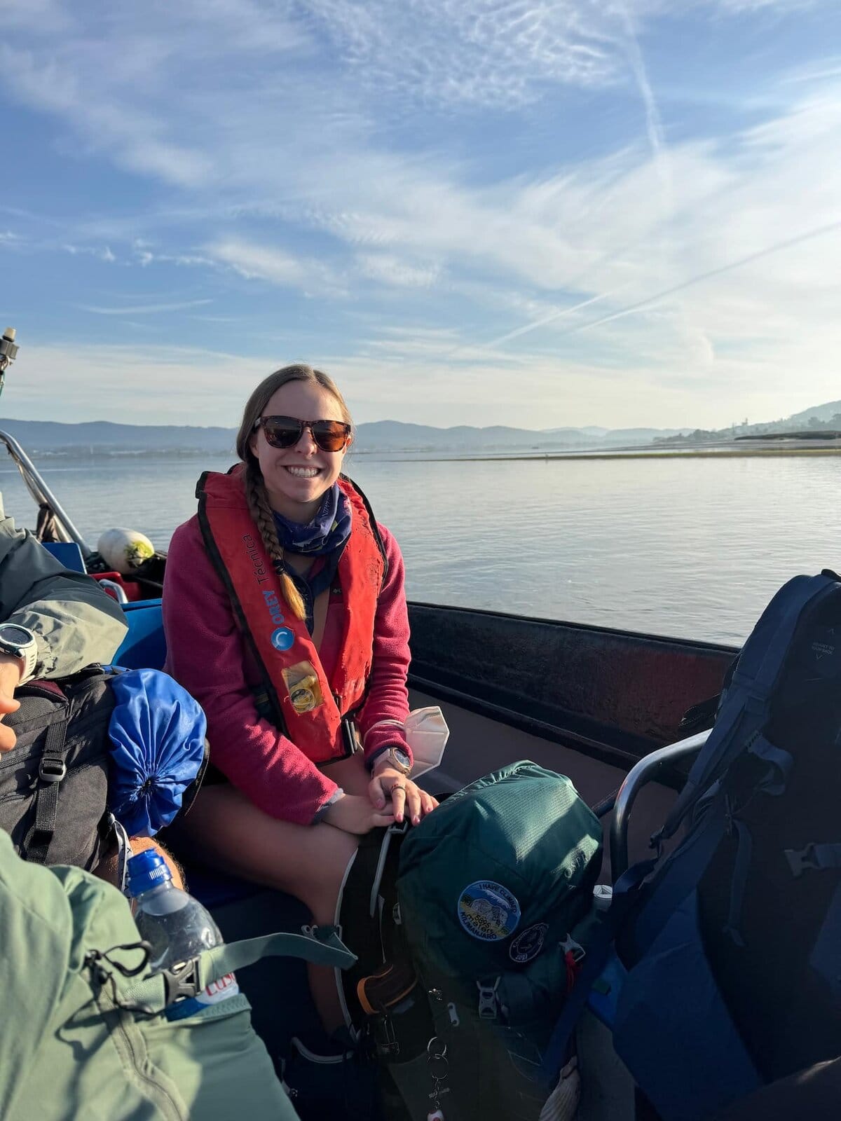 Mikala smiling wearing a life jacket on a small boat to cross the river from Caminha, Portugal into Spain along the Camino Portugués Coastal.