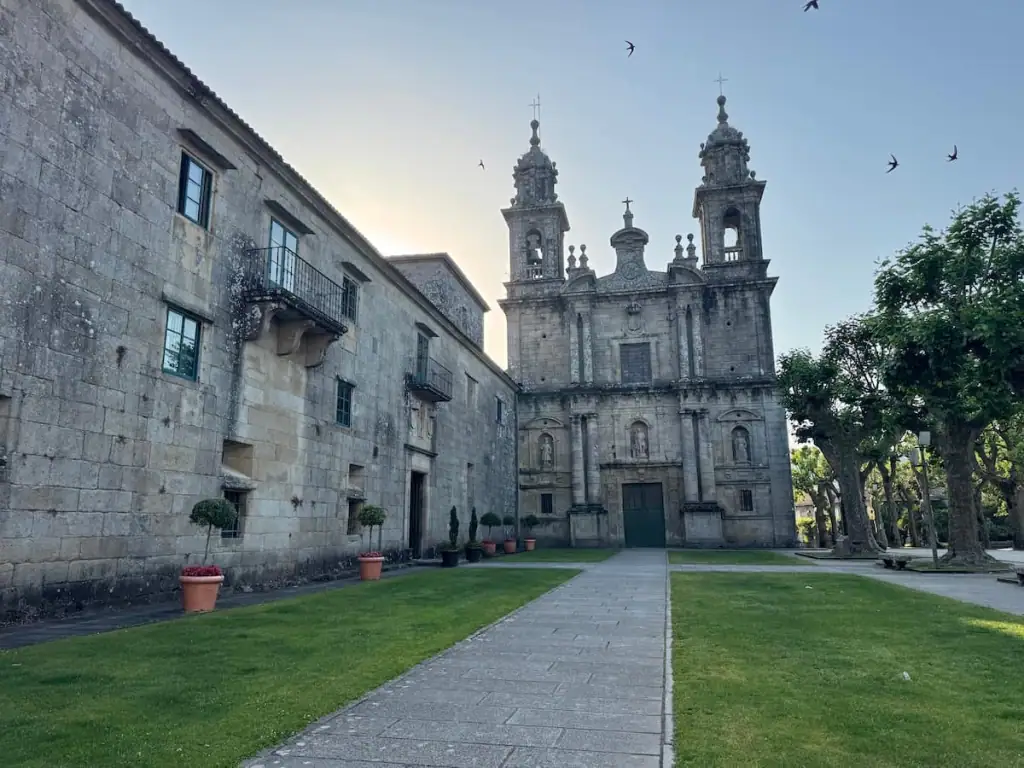 The monastery in Poio with birds flying around it in the sky. This is one of the highlights along the Camino Spiritual Variant.