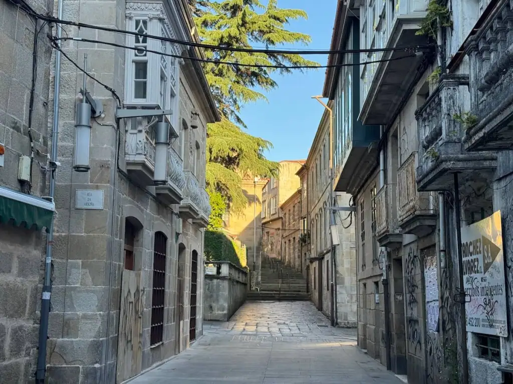 Empty narrow cobblestone street with old stone buildings on both sides in the morning in Pontevedra, Spain on the Camino de Santiago.