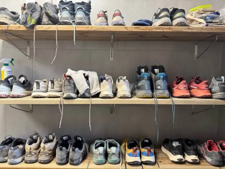 Three shelves full of shoes at an albergue on the Camino Portugués.