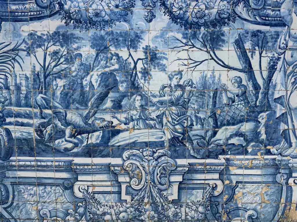 Close up image of some of the painted blue azulejo tiles in the Porto Cathedral. This set of tiles shows a few figures that look like angels and a small dragon.