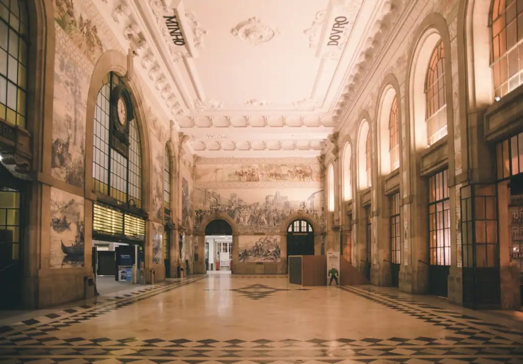 Empty entrance hall at São Bento Train Station in Porto, Portugal with a high white ceiling and walls covered in blue painted azulejo tiles.