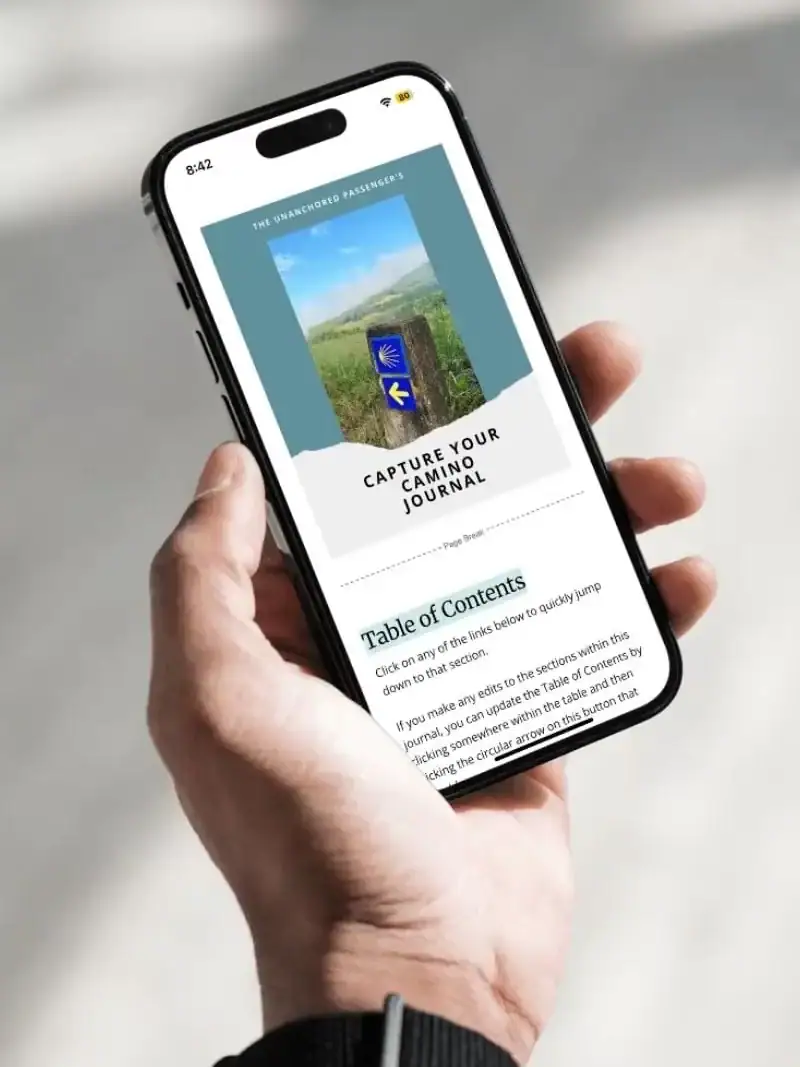 Hand holding a phone showing the Capture Your Camino Journal on it.