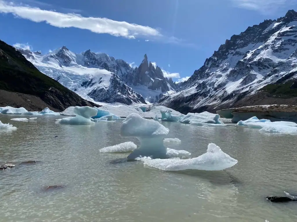 Icebergs floating on the Laguna Torre glacial lake surrounded by rugged mountains and the towering spires of Cerro Torre in the background. Trekking to this breathtaking viewpoint is a must for any hikers visiting El Chaltén on their Argentina itinerary.
